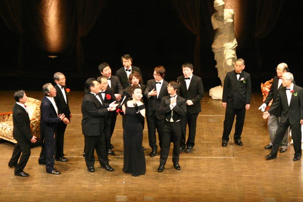 別府市 ビーコンプラザオペレッタ劇場『メリーウィドウ』 - 「大金持ちの未亡人ハンナ(里中トヨコさん)」に求愛する男声合唱の方々